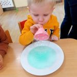 Chłopiec dmucha w lejek aby wyszła kolorowa bańka mydlana