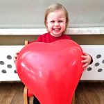 Uśmiechnięta dziewczynka z balonem w kształcie serca