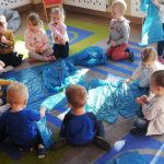 Dzieci słuchają jak opiekunka opowiada o podwodnym świecie