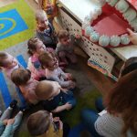 Dzieci słuchają jak ciocia opowiada o szczotkowaniu ząbków