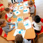 Dzieci przyklejają niebieską bibułę na wydrukowaną planetę