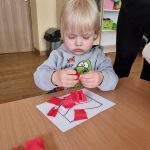Chłopiec przykleja czerwoną bibułę do flagi Polski