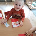 Uśmiechnięty chłopiec przykleja puzzle z flagą Polski