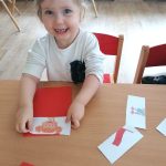 Uśmiechnięta Mia przykleja puzzle z flagą Polski
