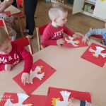 Dzieci przyklejają Godło Polski na czerwoną kartkę