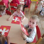 Dzieci przyklejają Godło Polski na czerwoną kartkę