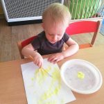 Chłopiec maluje słoneczko farbą