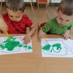 Mateusz i Jurek malują konewki zieloną farbą
