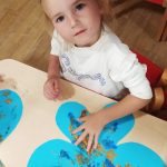 Dziewczynka maluje farbami motylka
