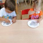 Chłopiec i dziewczynka malują talerz papierowy szarą farbą