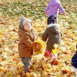 Dzieci bawią się liśćmi na dworze