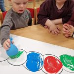 Jasiu wykonuje pracę plastyczną z użyciem farby i balonów