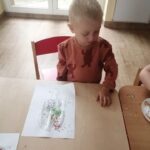 Dzieci przyklejają posypkę na kartkę papieru
