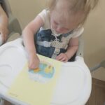 Dzieci przyklejają złotą rybkę na kartkę papieru