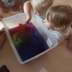 Dzieci oglądają eksperyment chemiczny z farbowaniem wody