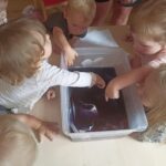 Dzieci oglądają eksperyment chemiczny z farbowaniem wody