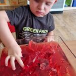 Dzieci biorą udział w zajęciach sensorycznych z galaretką owocową