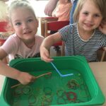 Dzieci wyławiają recepturki z wody za pomocą słomki