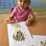 Dzieci przyklejają nasiona słonecznika i płatki kwiatów na kartkę