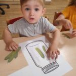 Dzieci naklejają papierowe ogórki na kartkę