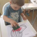 Dzieci wykonują pracę plastyczną z użyciem gąbki i farby na Dzień arbuza