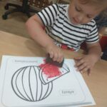 Dzieci wykonują pracę plastyczną z użyciem gąbki i farby na Dzień arbuza
