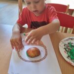 Dzieci wykonują pracę plastyczną z jabłkiem