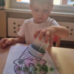 Dzieci kolorują kredkami i posypują kartkę brokatem