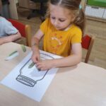 Dzieci naklejają papierowe ogórki na kartkę