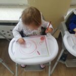 Dzieci uczą się chwytu pisarskiego przez malowanie kredkami po kartce papieru
