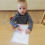 Dzieci uczą się chwytu pisarskiego przez malowanie kredkami po kartce papieru