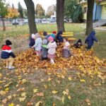 Dzieci bawią się w liściach na dworze