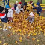 Dzieci bawią się w liściach na dworze