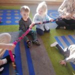 Dzieci ćwiczą rytmikę z gumą w kole