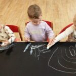 Dzieci rysują kredą po brystolu