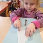 Dzieci wykonują pracę plastyczną z wykorzystaniem serwetki i patyczka