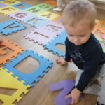 Dzieci układają piankowe puzzle z literkami