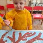 Dzieci wykonują pracę plastyczną z użyciem plastikowych słomek i farby